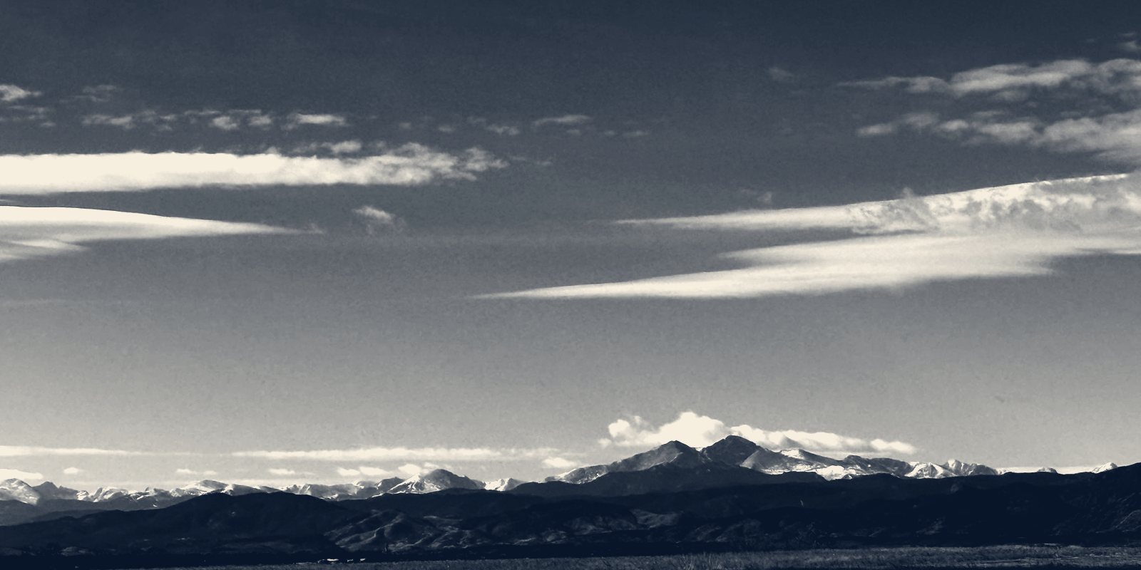 Long streaks of cloud above a distant mountain range