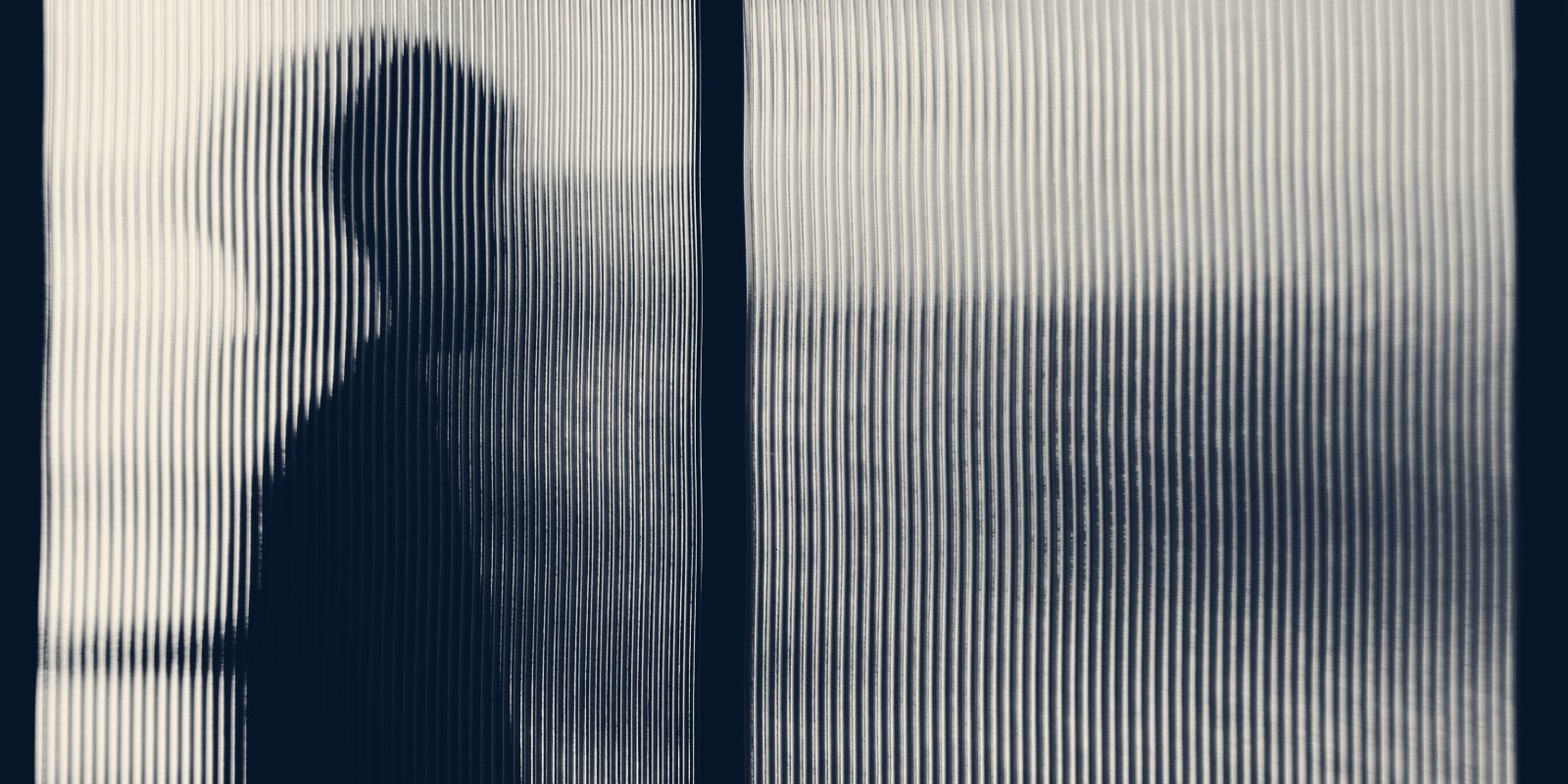 The blurred silhouette of a person standing behind ribbed glass