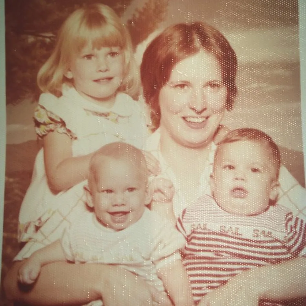 Vintage family photograph of a woman holding two babies, with a young girl beside her