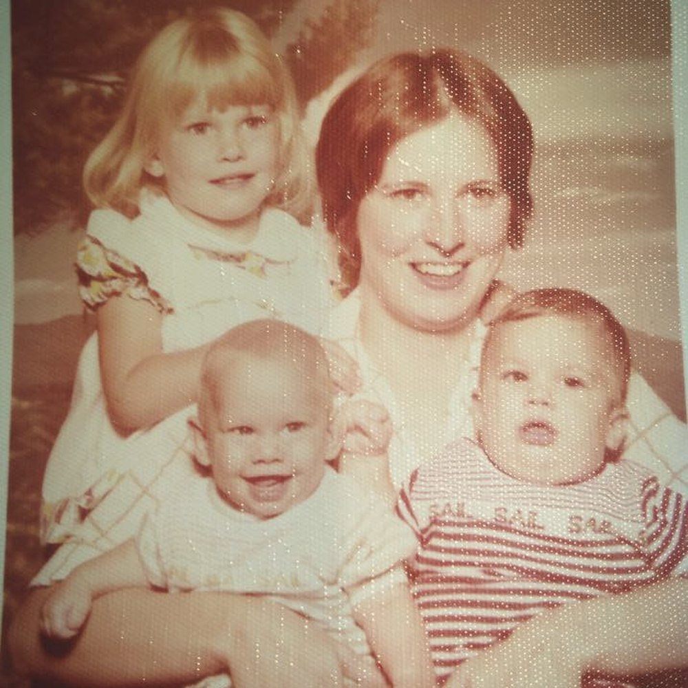 Vintage family photograph of a woman holding two babies, with a young girl beside her
