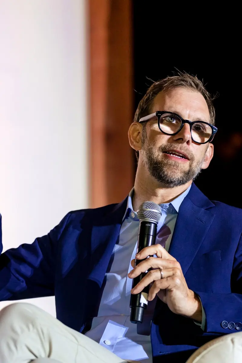 Michael Kutcher in conversation on stage, microphone in hand