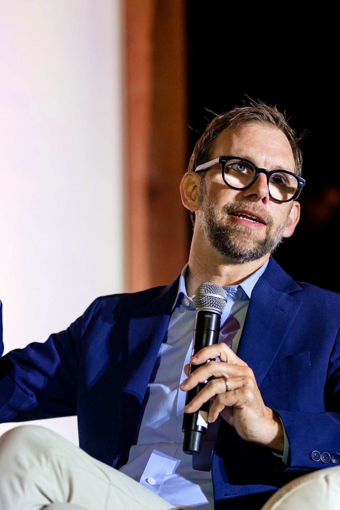 Michael Kutcher in conversation on stage, microphone in hand